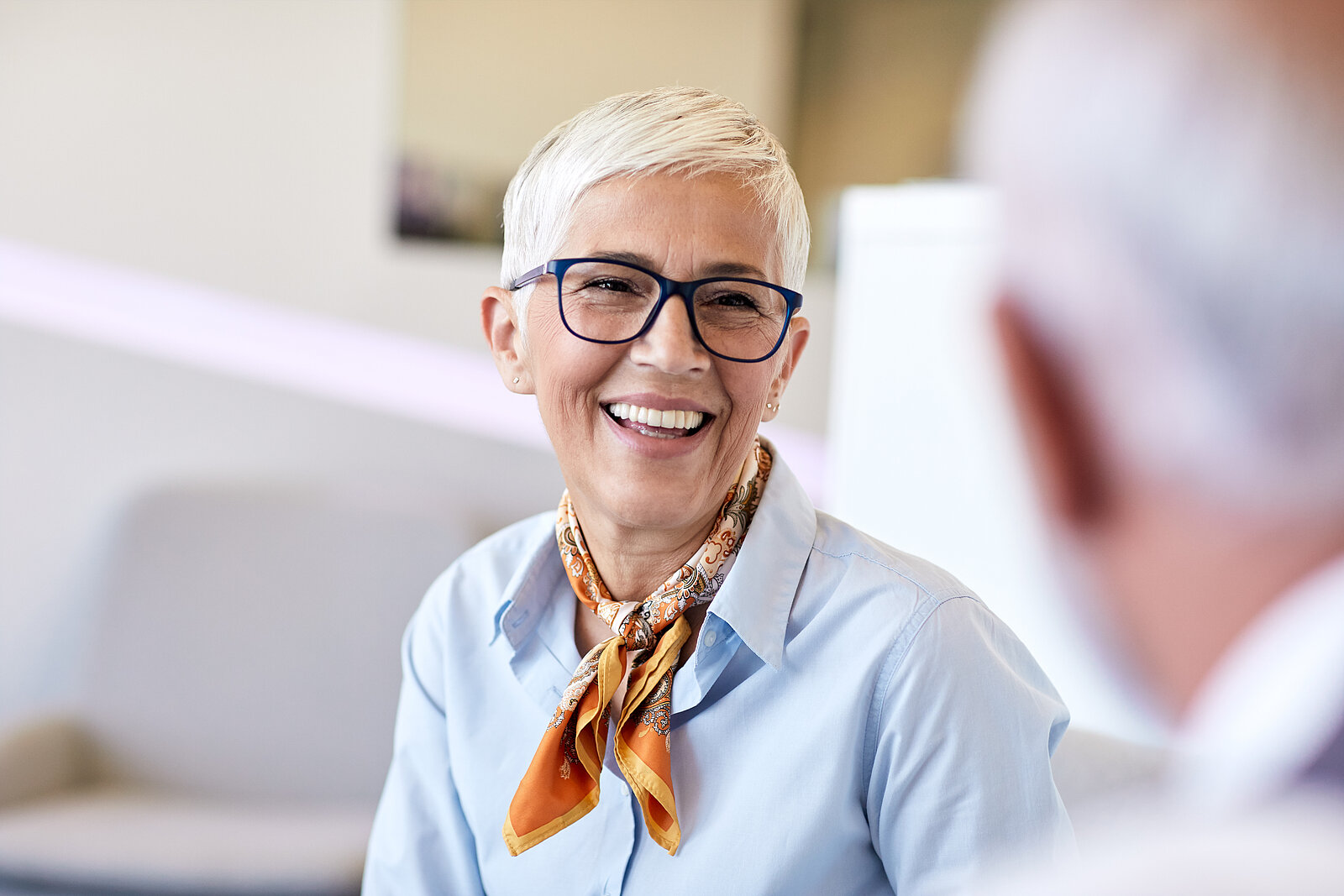 Frau mittleren Alters mit Brille lächelt ihren Gesprächspartner an